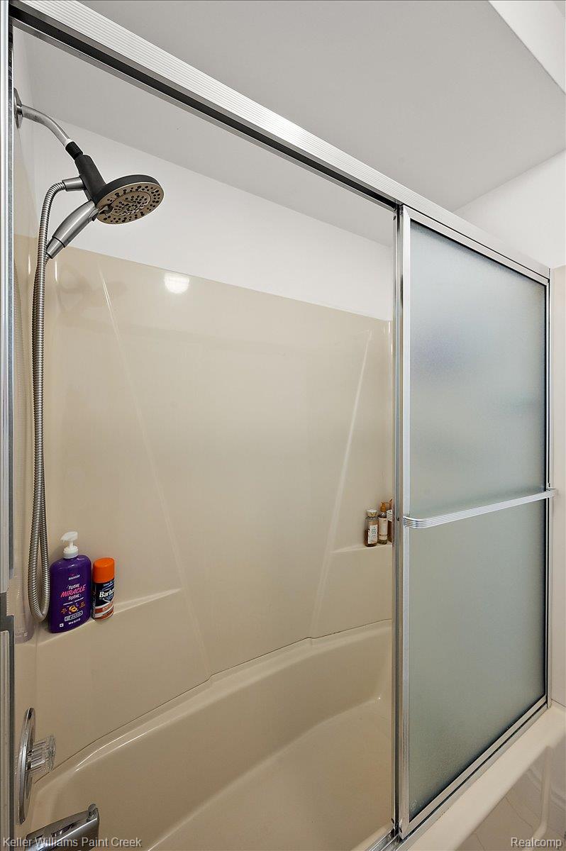 69069 Campground Road Romeo, MI 48065 - Photo 56 of 78 Bathtub and shower combination featuring a multi-setting shower head, chrome fixtures, and a sliding frosted glass enclosure