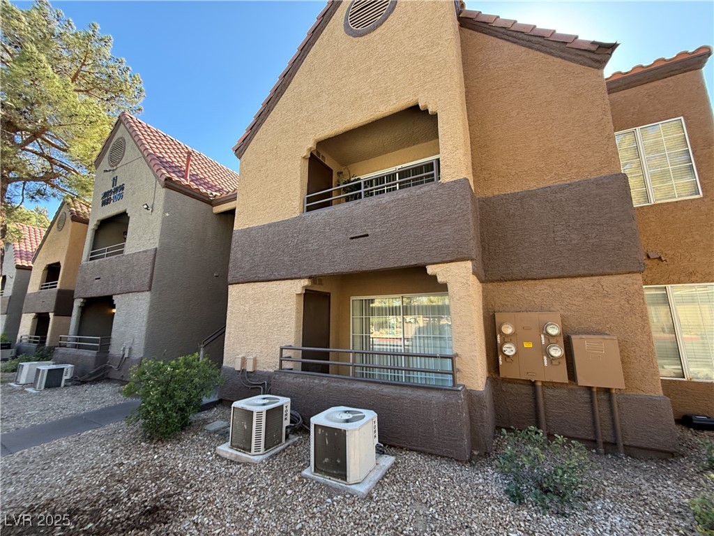 Back of house featuring stucco siding, a tile roof, and a balcony