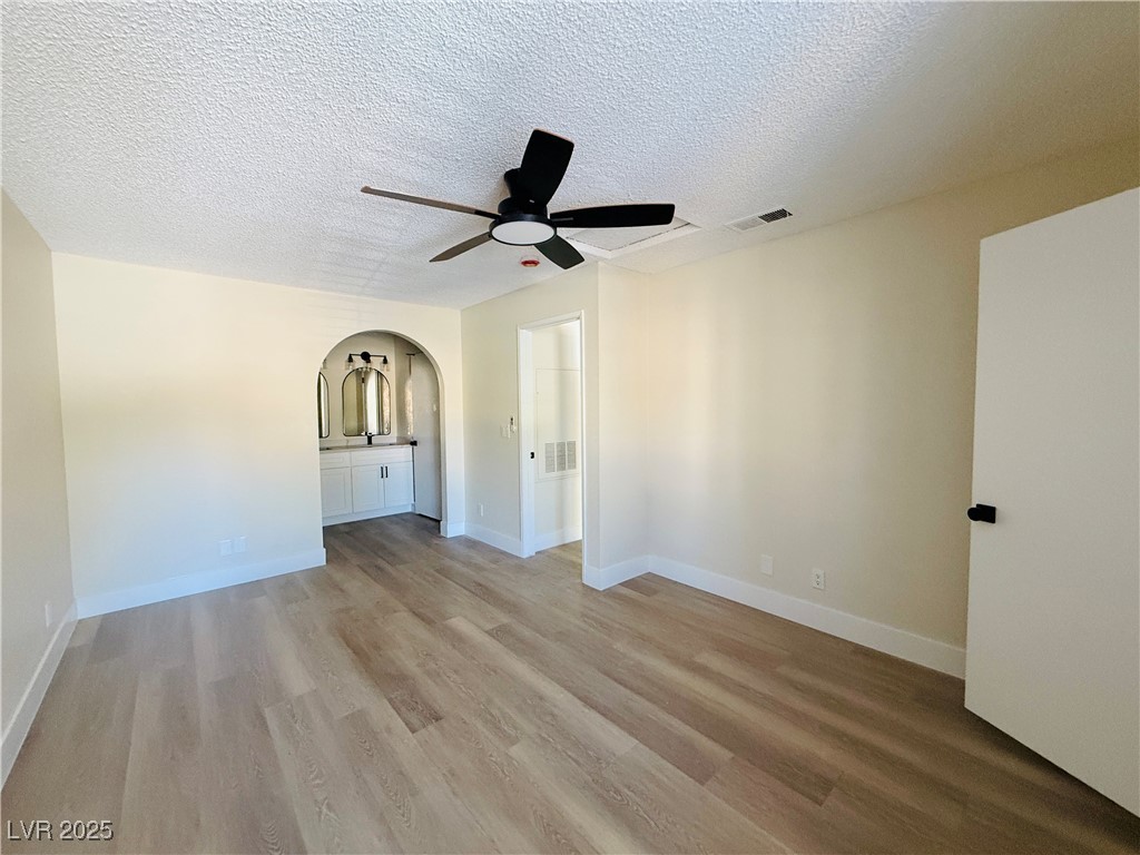 2200 South Fort Apache Road, Unit 2095 Las Vegas, NV 89117 - Photo 6 of 16 Spare room featuring arched walkways, a ceiling fan, a textured ceiling, and light wood-style floors