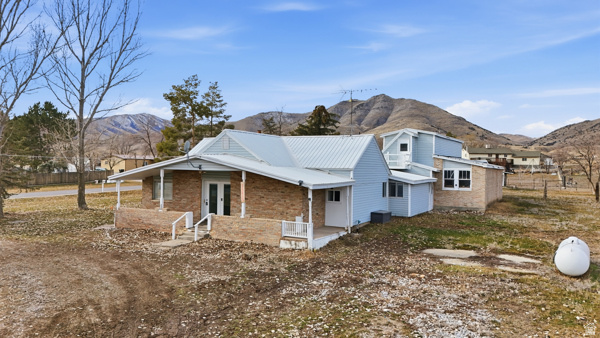 25615 Main Street Portage, UT 84331 - Photo 1 of 42 View of property exterior featuring covered porch, a mountain view, brick siding, double doors, and a metal roof