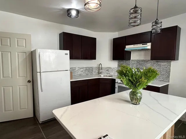 a kitchen with stainless steel appliances kitchen island granite countertop a refrigerator a sink a stove with a dining table and chairs