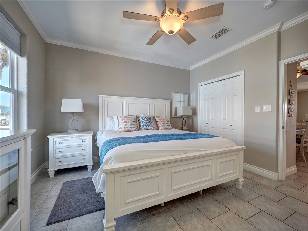 1833 Eleventh Street, Unit F2 Port Aransas, TX 78373 - Photo 17 of 40 a bedroom with a bed and a chandelier