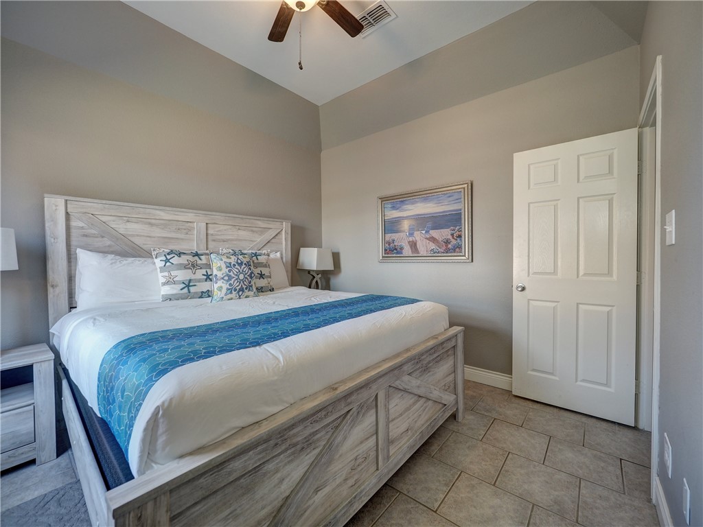 1833 Eleventh Street, Unit F2 Port Aransas, TX 78373 - Photo 24 of 40 a bedroom with a bed and a chandelier