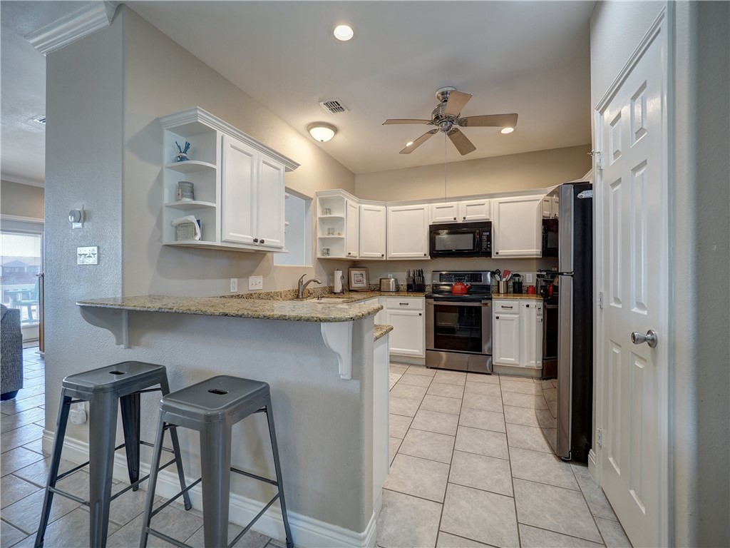 1833 Eleventh Street, Unit F2 Port Aransas, TX 78373 - Photo 3 of 40 a kitchen with granite countertop a refrigerator stove top oven and sink
