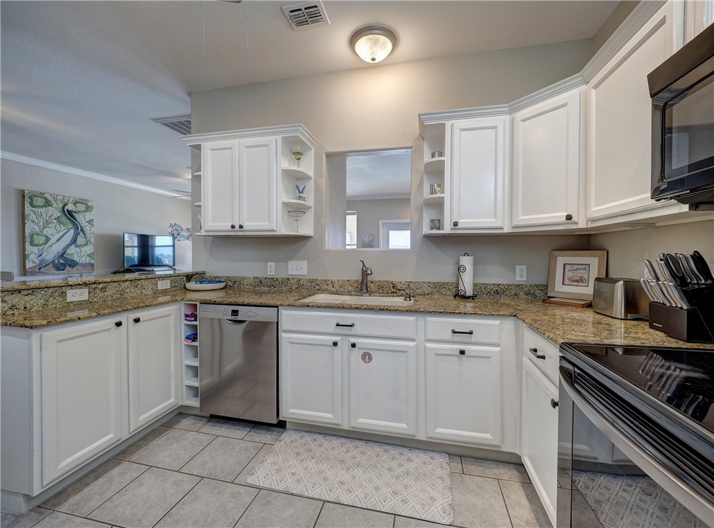 1833 Eleventh Street, Unit F2 Port Aransas, TX 78373 - Photo 4 of 40 a kitchen with granite countertop cabinets stainless steel appliances and a sink