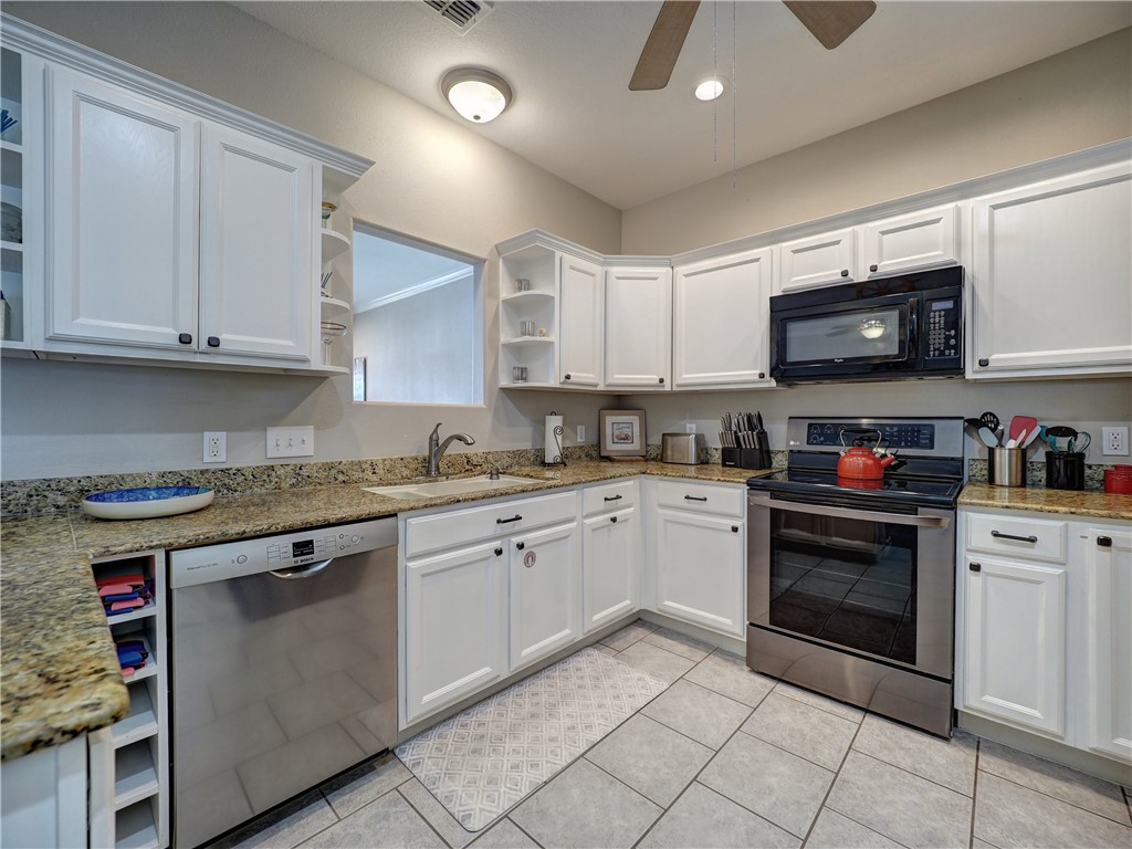 1833 Eleventh Street, Unit F2 Port Aransas, TX 78373 - Photo 6 of 40 a kitchen with granite countertop a stove top oven sink and cabinets