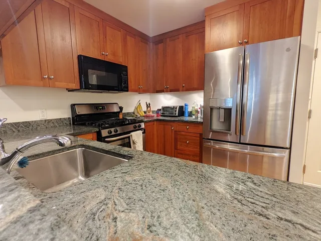 a kitchen with granite countertop a refrigerator and a sink