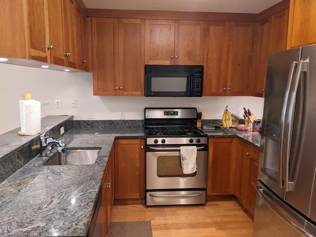 a kitchen with stainless steel appliances granite countertop a refrigerator stove and sink