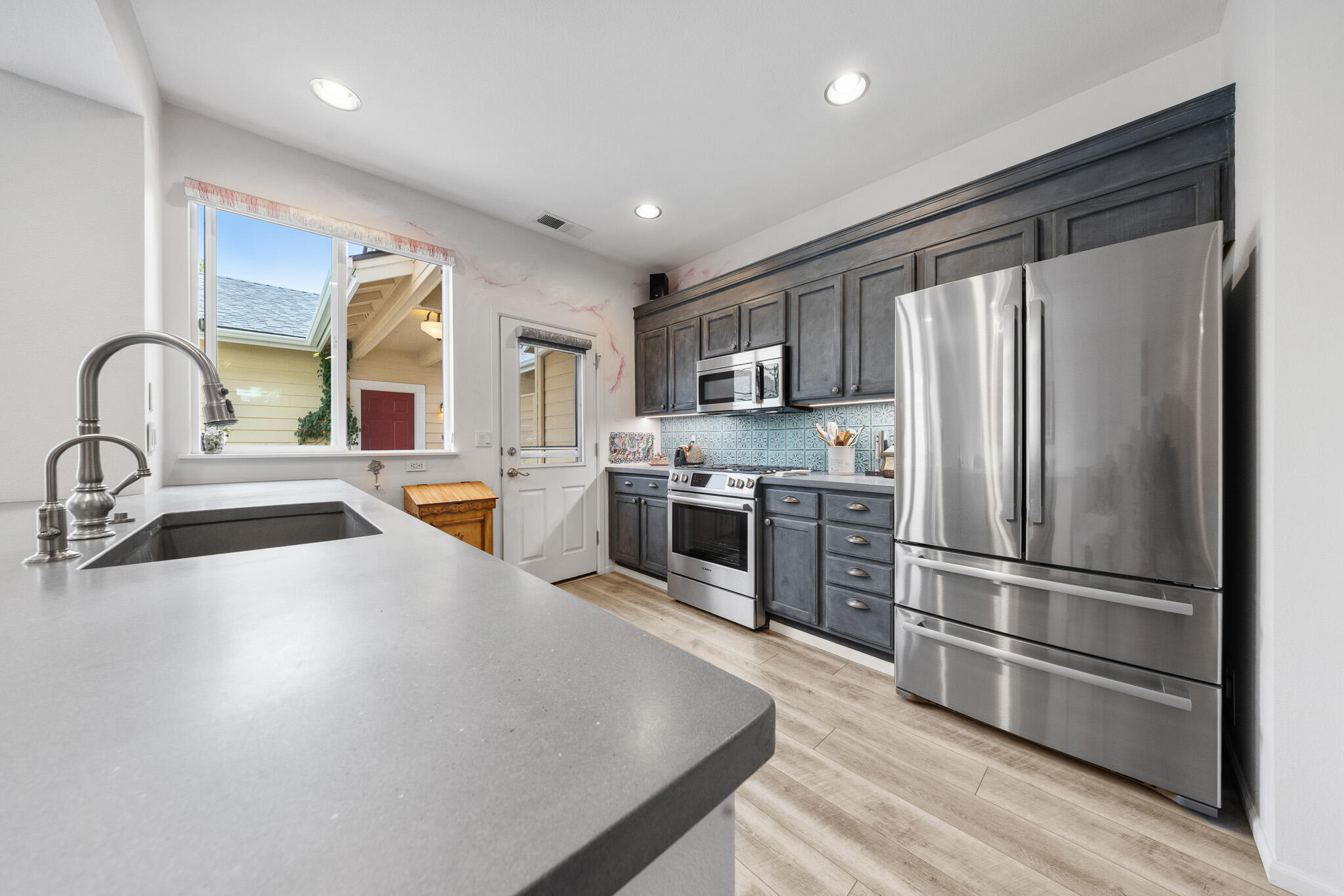 624 Southwest Hill Street Bend, OR 97702 - Photo 8 of 45 a kitchen with stainless steel appliances granite countertop a refrigerator a sink a stove and a microwave with wooden floor