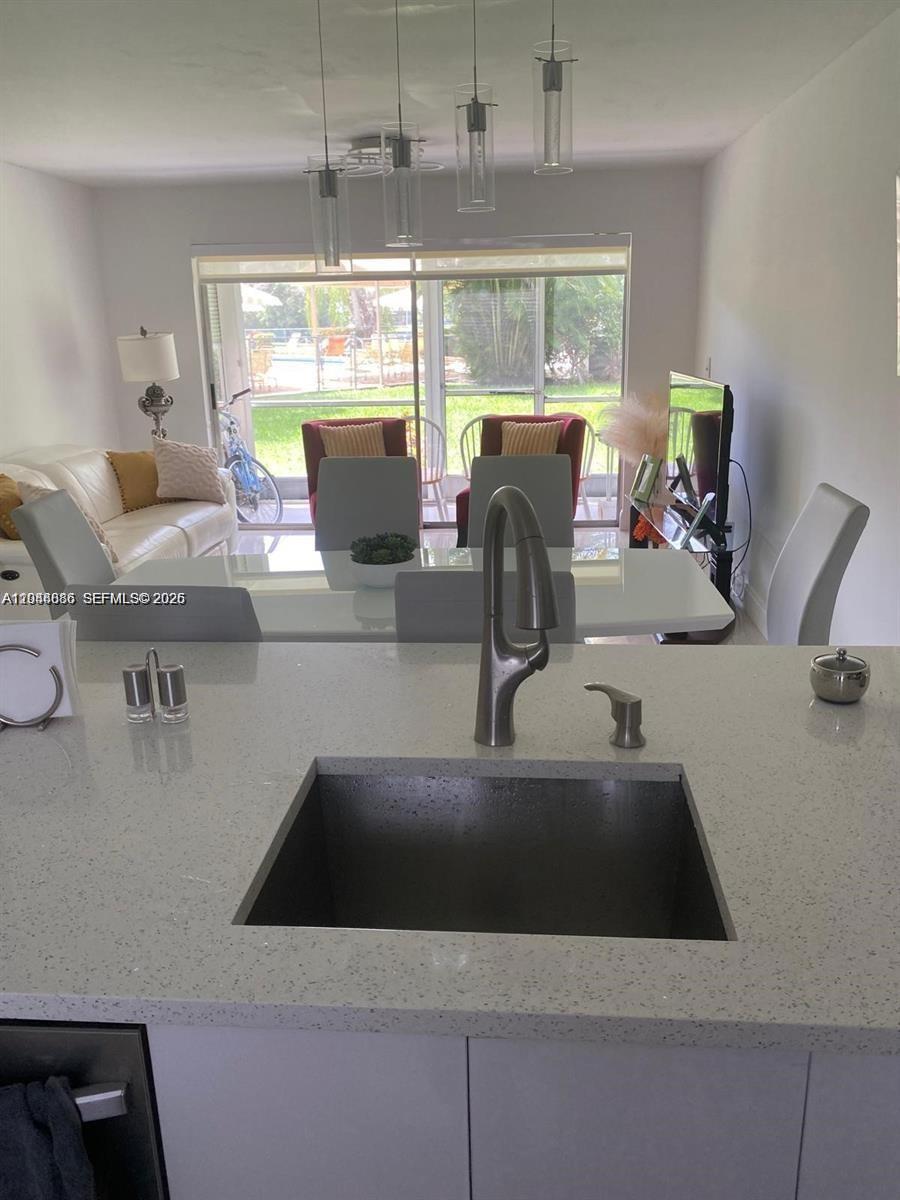 8838 West McNab Road, Unit 104 Tamarac, FL 33321 - Photo 4 of 23 a view of a kitchen with kitchen island a large window a sink and living room view