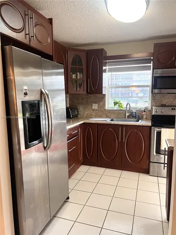 a kitchen with stainless steel appliances granite countertop a sink a stove a refrigerator and cabinets