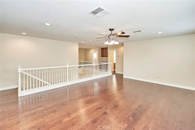 wooden floor in an empty room with a chandelier fan