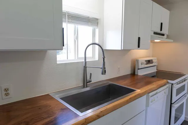 a view of a sink a stove and kitchen island with wooden floor