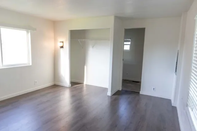 an empty room with wooden floor & windows