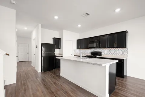 a kitchen with granite countertop a stove top oven sink and cabinets
