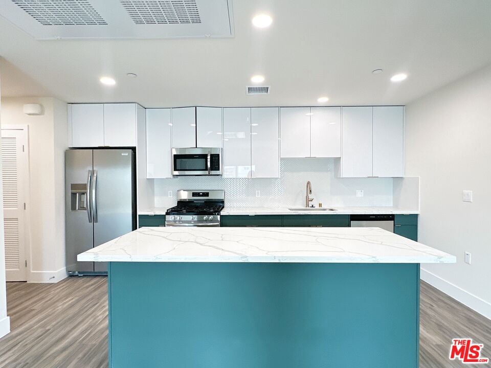 a kitchen with kitchen island a sink stainless steel appliances and cabinets