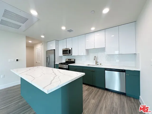 a kitchen with stainless steel appliances kitchen island sink refrigerator stove and wooden cabinets