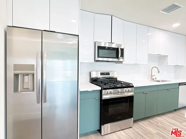 a kitchen with cabinets stainless steel appliances and a wooden floor