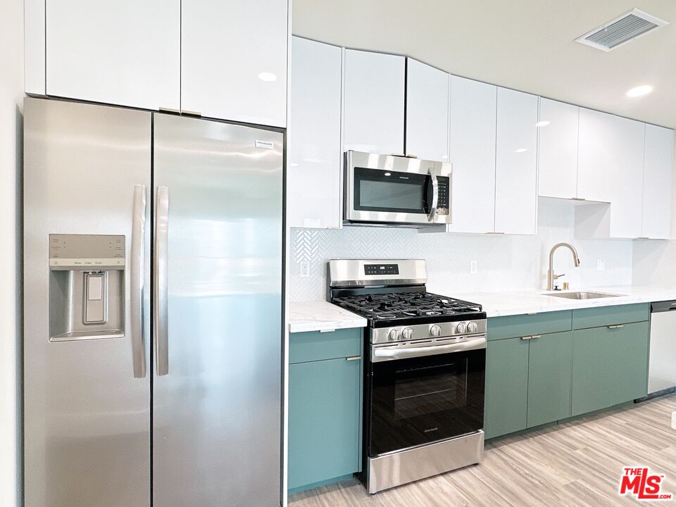 1037 Dewey Avenue, Unit 501 Los Angeles, CA 90006 - Photo 3 of 11 a kitchen with cabinets stainless steel appliances and a wooden floor
