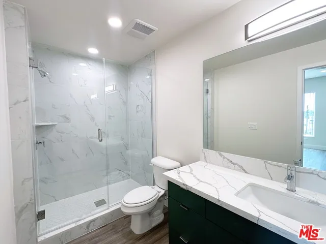 a bathroom with a granite countertop sink a toilet and shower