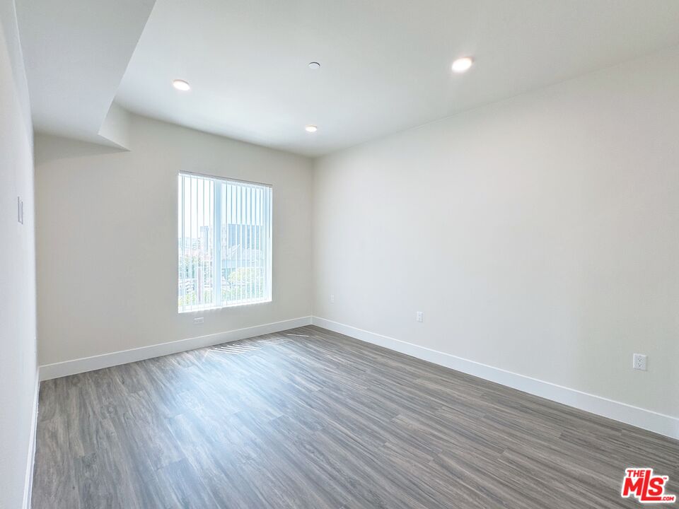 1037 Dewey Avenue, Unit 501 Los Angeles, CA 90006 - Photo 5 of 11 an empty room with wooden floor and windows