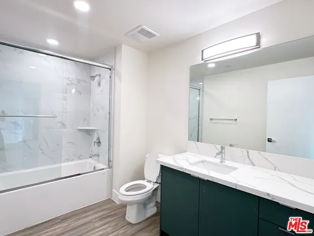 a bathroom with a bathtub shower sink vanity mirror and toilet