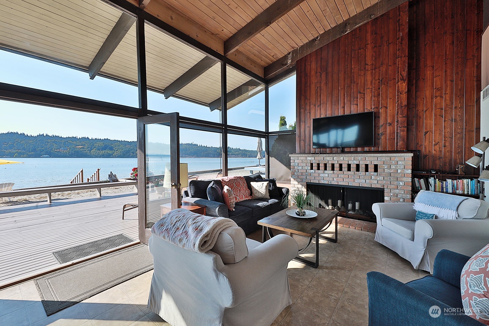 8166 Sandy Hook Drive Clinton, WA 98236 - Photo 11 of 40 a living room with furniture a fireplace a flat screen tv and floor to ceiling window
