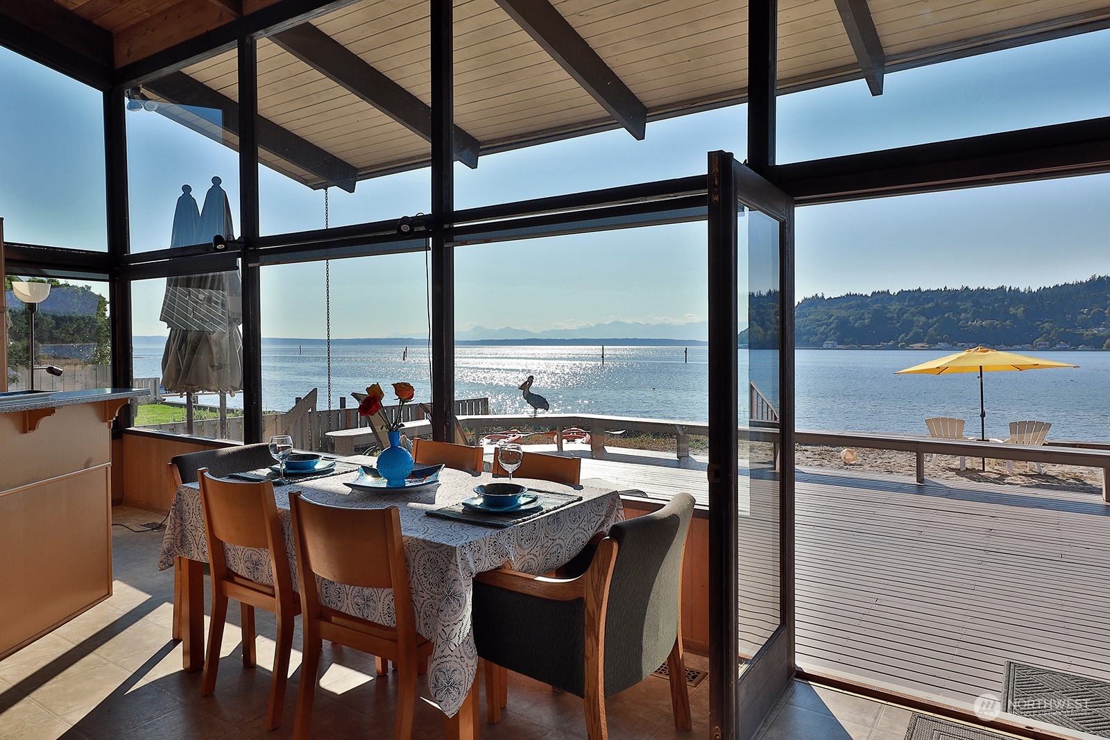 8166 Sandy Hook Drive Clinton, WA 98236 - Photo 13 of 40 a view of a dining room with furniture large windows and a chandelier