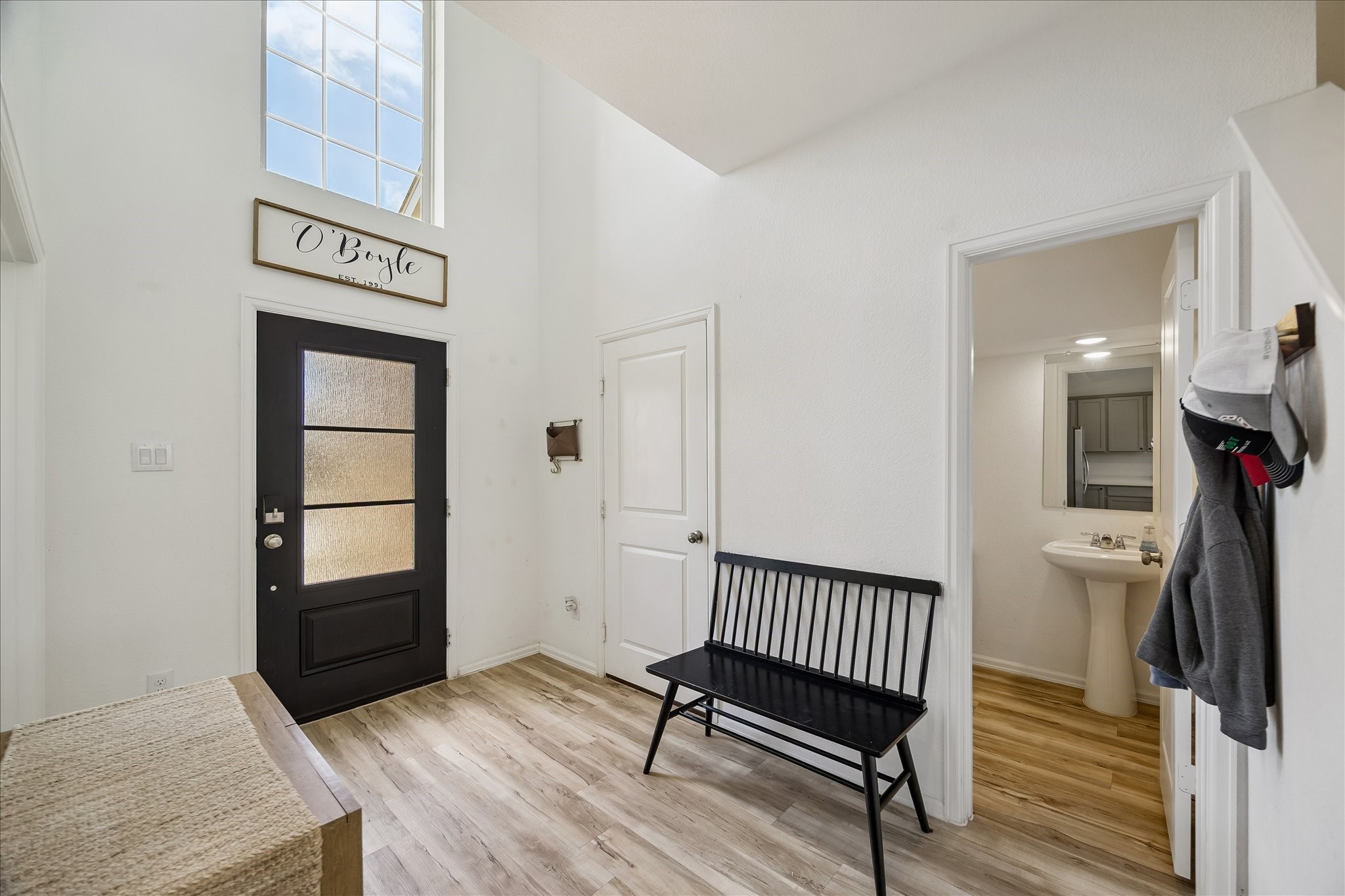 3812 Moss Hl Road Rosenberg, TX 77469 - Photo 8 of 20 Bright entryway featuring a modern black front door and high windows. The spacious foyer with access to a half bathroom with a pedestal sink. The light wood flooring adds warmth.