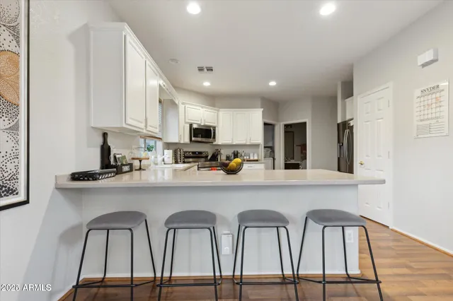 a kitchen with stainless steel appliances granite countertop a table chairs sink and cabinets