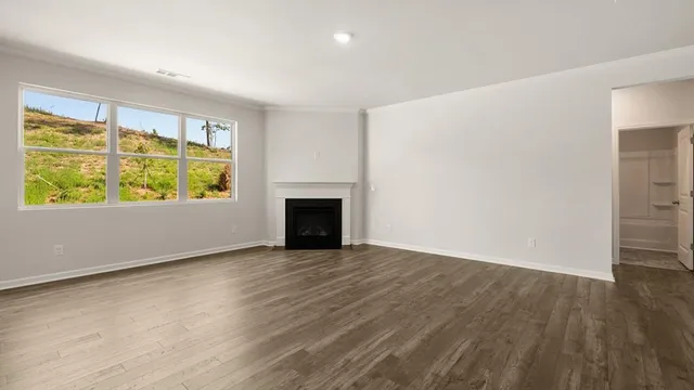 an empty room with wooden floor fireplace and windows
