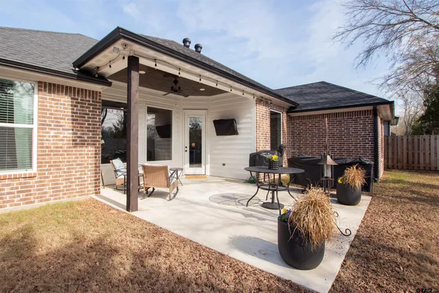 a view of a patio with table and chairs and wooden fence