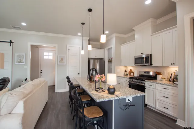 a kitchen with stainless steel appliances kitchen island granite countertop a sink a stove a dining table and chairs