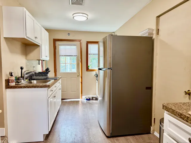 a kitchen with granite countertop a refrigerator and a sink