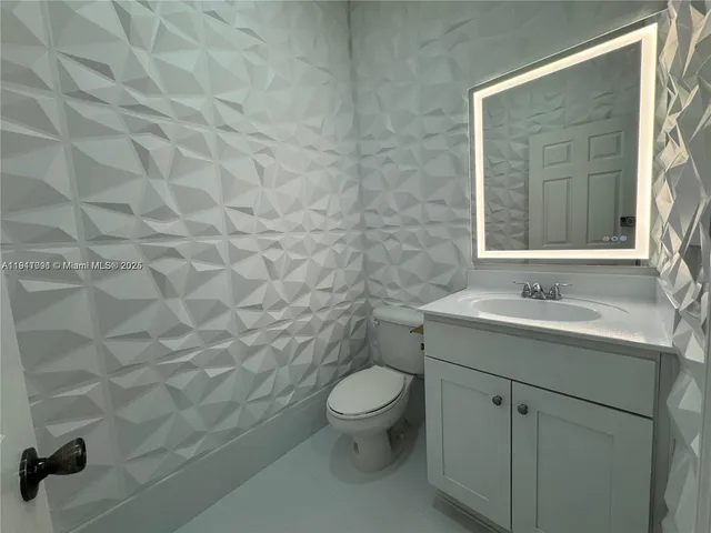 a bathroom with a granite countertop toilet a sink and mirror