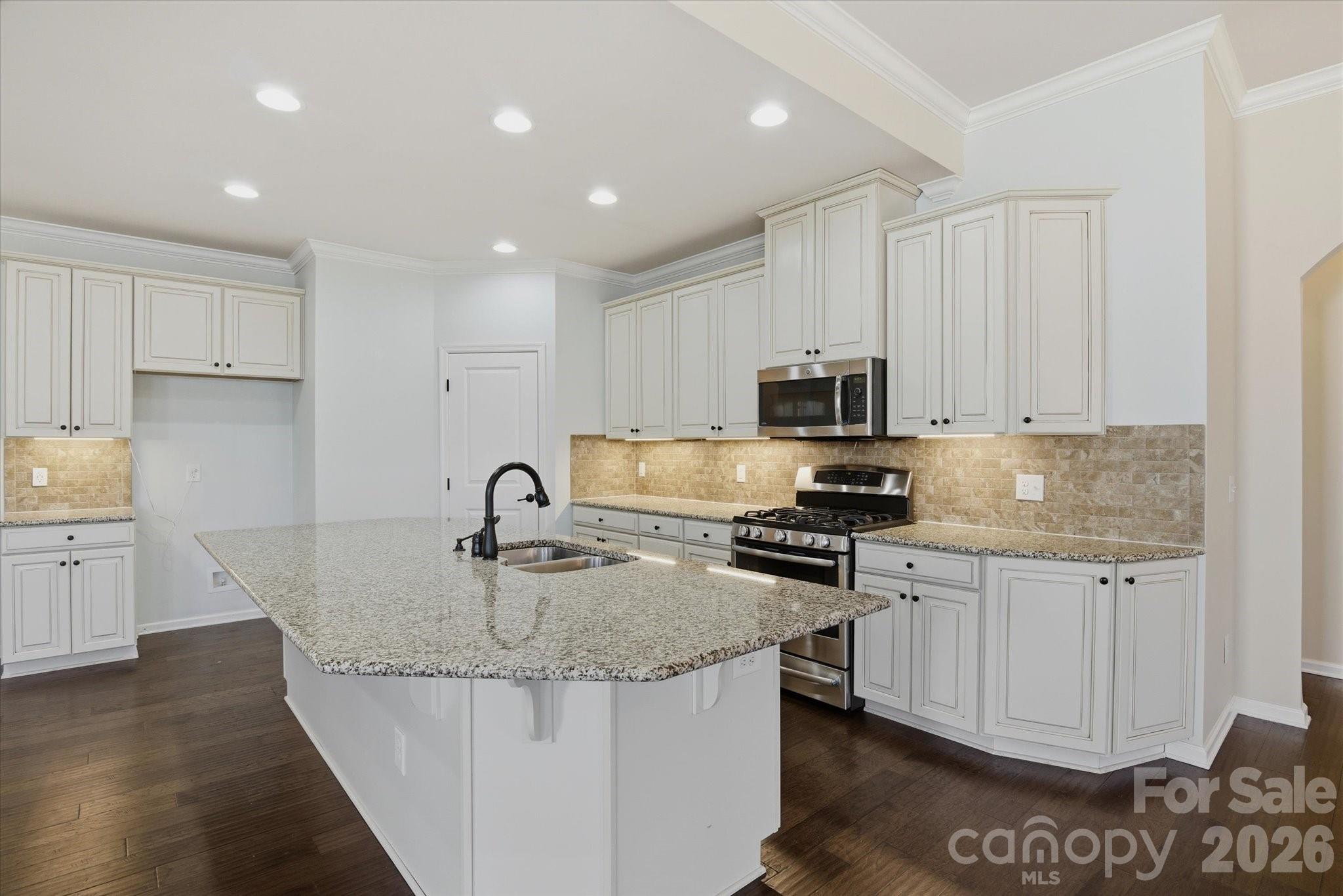 5009 St Clair Street Fort Mill, SC 29715 - Photo 15 of 40 a kitchen with kitchen island granite countertop a stove sink and cabinets