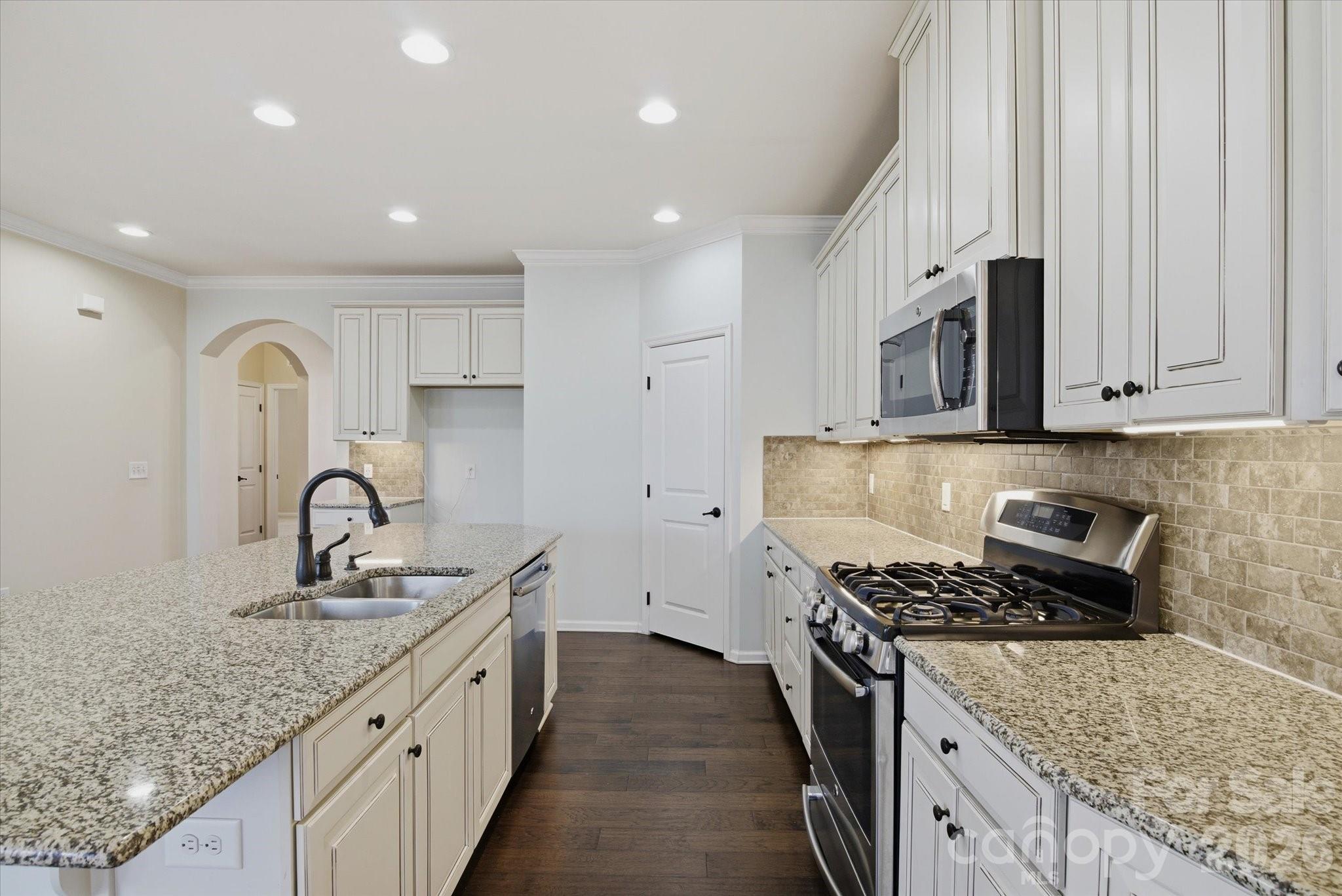 5009 St Clair Street Fort Mill, SC 29715 - Photo 18 of 40 a kitchen with granite countertop a sink stainless steel appliances and white cabinets