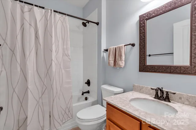 a bathroom with a granite countertop sink vanity mirror and toilet