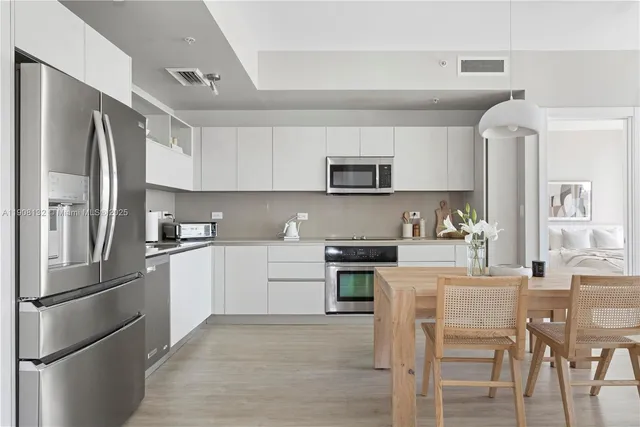 a kitchen with stainless steel appliances granite countertop a refrigerator a stove a sink a stove a dining table and chairs