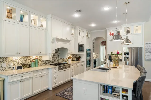 a large kitchen with cabinets chairs and wooden floor