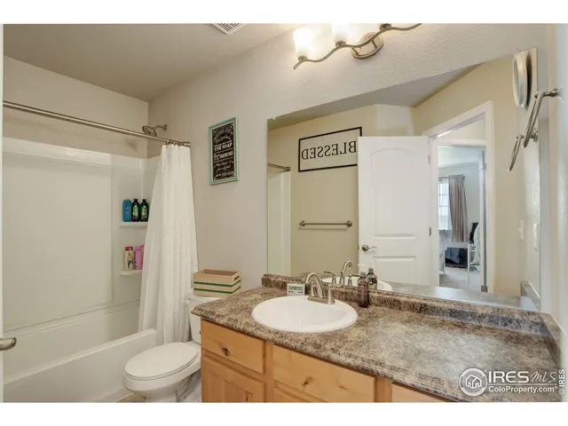 a bathroom with a granite countertop sink a toilet a mirror and shower