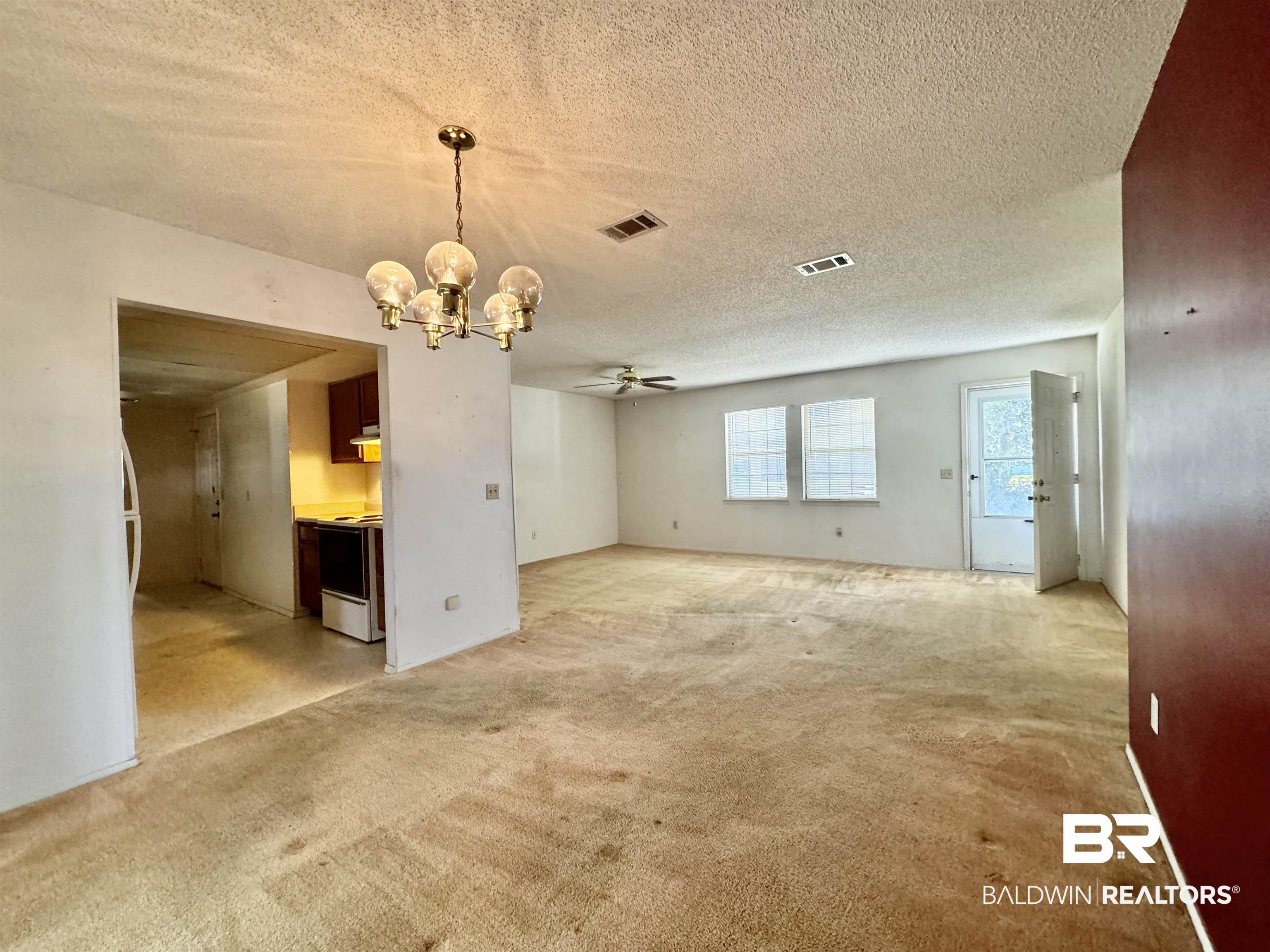 512 Deborah Court Foley, AL 36535 - Photo 14 of 23 Unfurnished living room featuring ceiling fan with notable chandelier, a textured ceiling, and light carpet