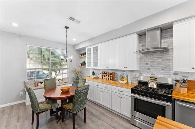 a kitchen with stainless steel appliances a sink a stove a table and chairs