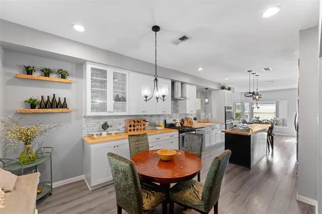 a kitchen with a dining table chairs stove and wooden floor