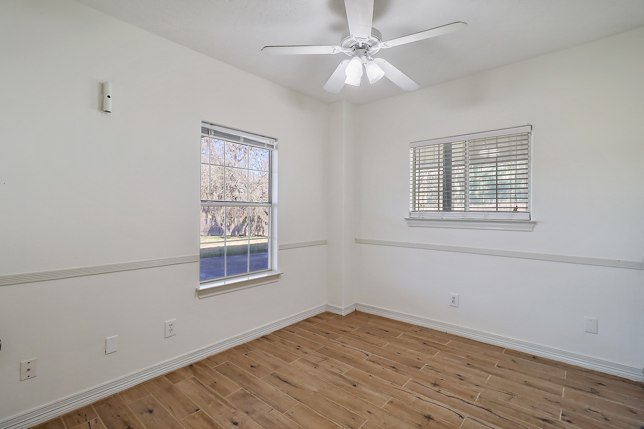 1306 Spring Branch Drive Baytown, TX 77523 - Photo 17 of 38 an empty room with wooden floor ceiling fan and windows