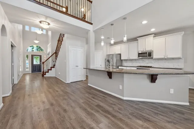 a kitchen with stainless steel appliances granite countertop a refrigerator a stove and a wooden floors