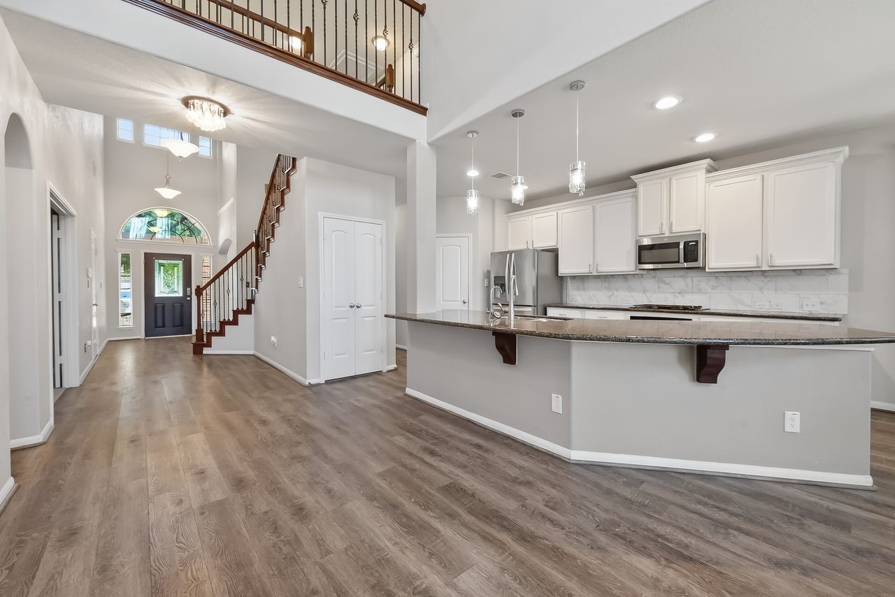 9151 Monarch Field Lane Cypress, TX 77433 - Photo 16 of 48 a kitchen with stainless steel appliances granite countertop a refrigerator a stove and a wooden floors