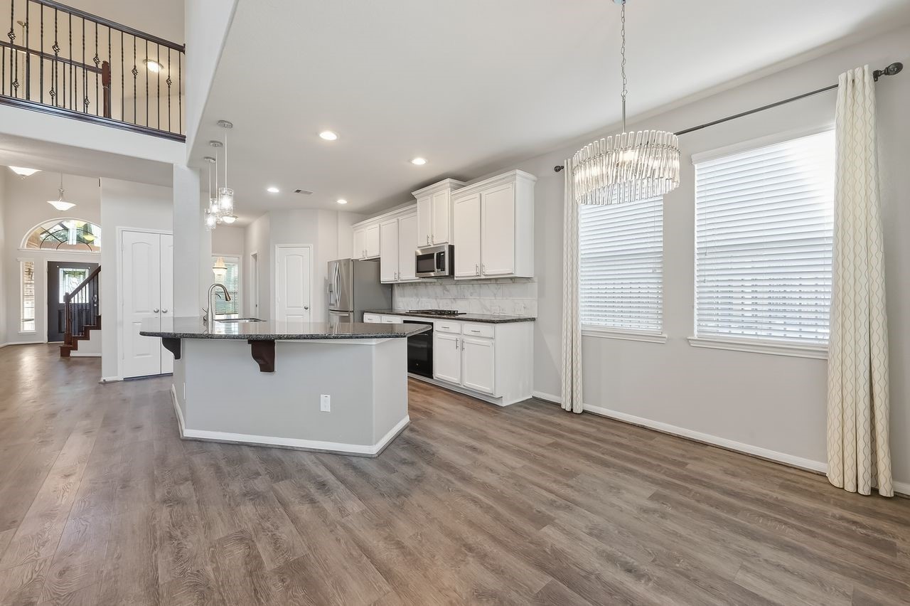 9151 Monarch Field Lane Cypress, TX 77433 - Photo 18 of 48 a view of kitchen with granite countertop kitchen island wooden floors stainless steel appliances and window