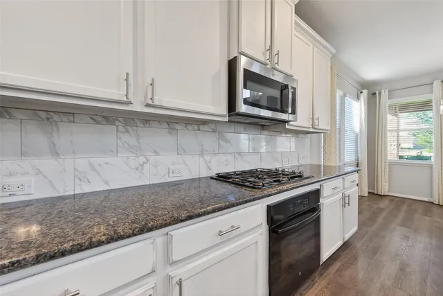 a kitchen with granite countertop white cabinets and stainless steel appliances