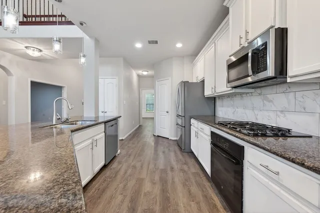 a kitchen with stainless steel appliances granite countertop a stove a sink and a microwave